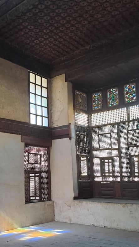 Inside Bayt al-Razzaz, with light falling through a wooden carved mashrabeya window
